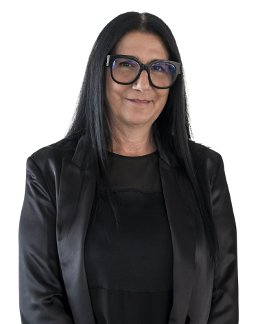 Frau mit Blazer, die die Arme verschränkt hält, vor weißem Hintergrund.