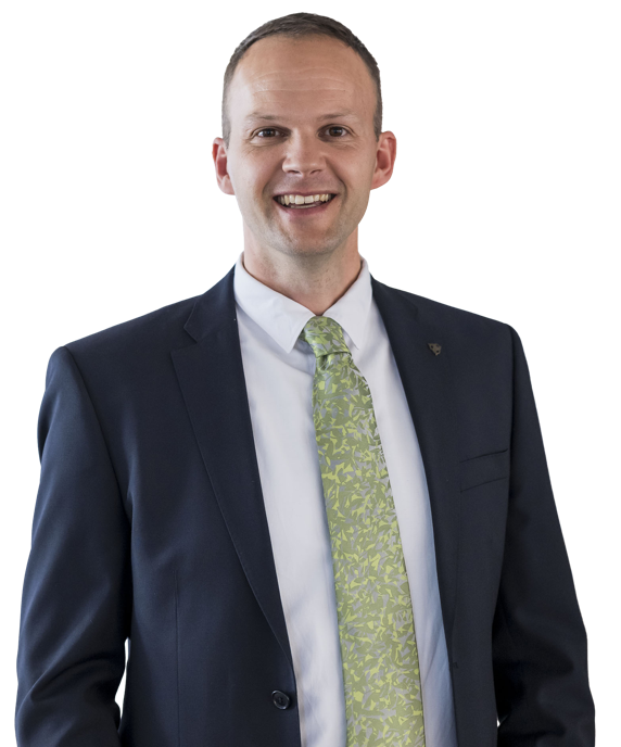 Eine lächelnde Person in einem Anzug und Hemd vor weißem Hintergrund.