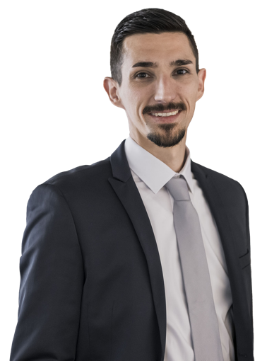 Eine lächelnde Person in einem Anzug und Hemd vor weißem Hintergrund.