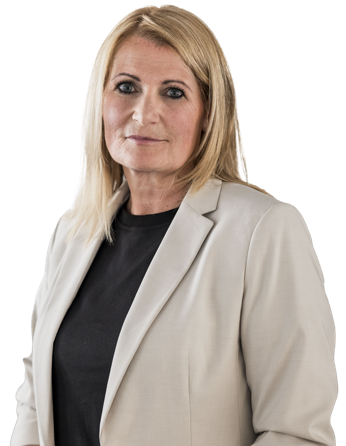 Frau mit Blazer, die die Arme verschränkt hält, vor weißem Hintergrund.