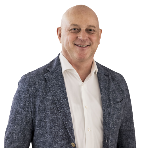 Eine lächelnde Person in einem Anzug und Hemd vor weißem Hintergrund.