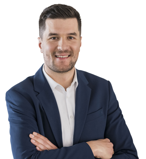 Eine lächelnde Person in einem Anzug und Hemd vor weißem Hintergrund.