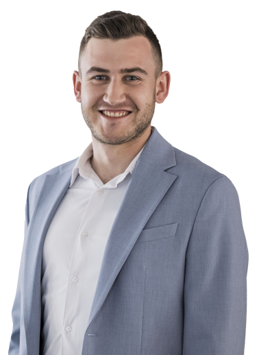 Eine lächelnde Person in einem Anzug und Hemd vor weißem Hintergrund.