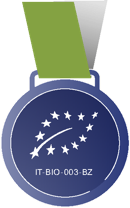 Blaues Medaillon mit grünem Band, darauf weiße Sterne in Form eines Blattes und der Text "IT-BIO-003-BZ".