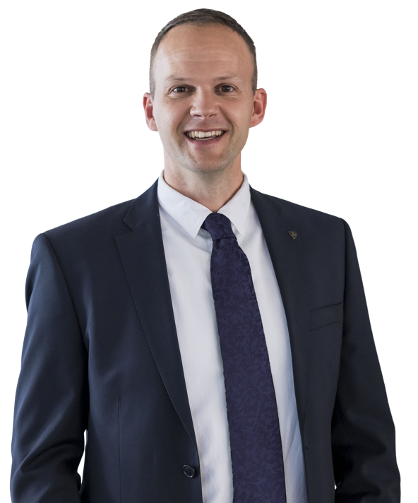 Ein Mann in einem dunklen Anzug mit weißem Hemd und dunkelblauer Krawatte lächelt in die Kamera.