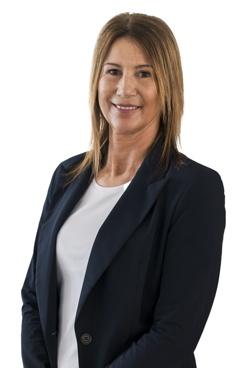 Frau mit Blazer, die die Arme verschränkt hält, vor weißem Hintergrund.