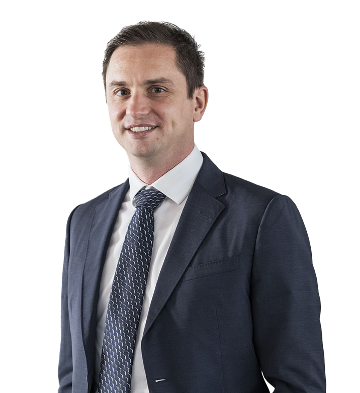 Ein Mann in einem blauen Anzug mit weißem Hemd und grauer Krawatte vor weißem Hintergrund.