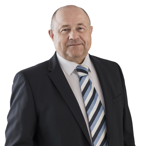 Eine lächelnde Person in einem Anzug und Hemd vor weißem Hintergrund.