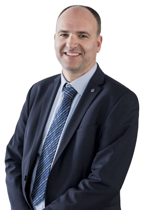 Eine lächelnde Person in einem Anzug und Hemd vor weißem Hintergrund.